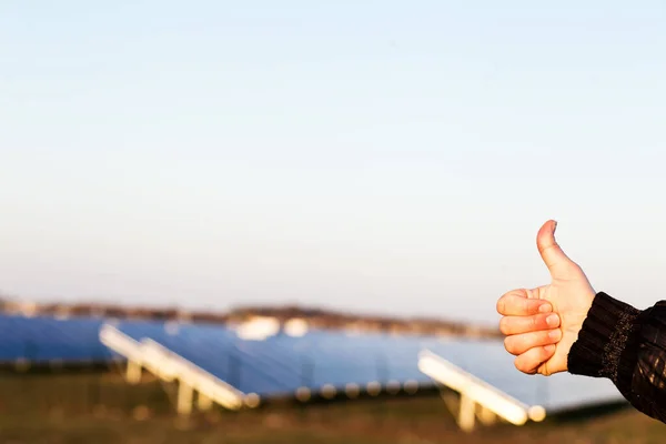 再生可能エネルギー源のための親指 太陽電池パネルを背景に親指を示す手 — ストック写真