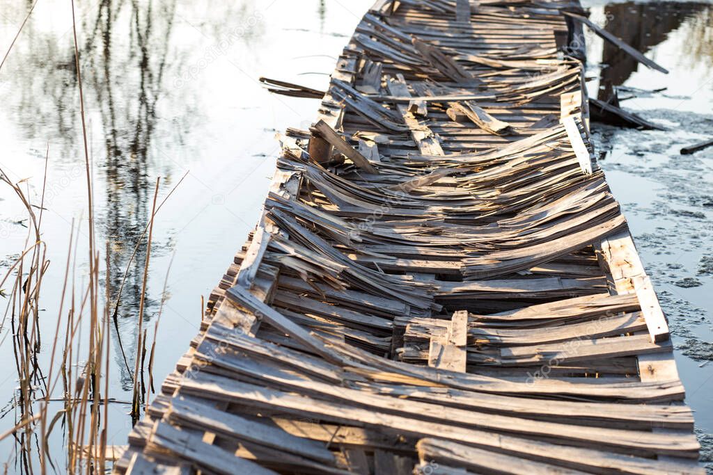 Dengerous old wooden bridge made of pallets over the river.