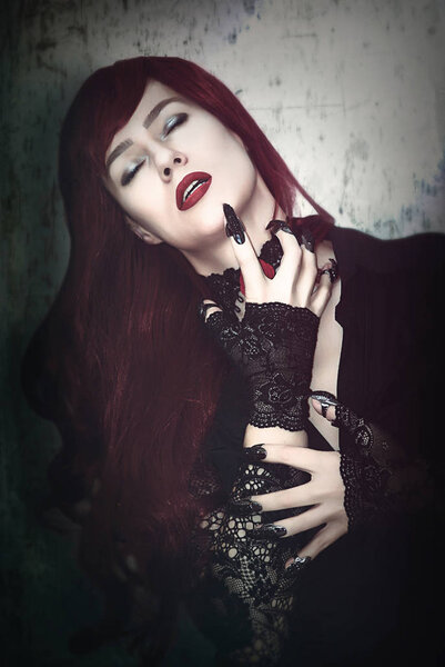 A woman is a vampire with red hair and black claws.