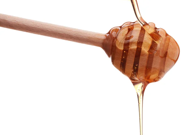 Honey dripping from wooden spoon — Stock Photo, Image