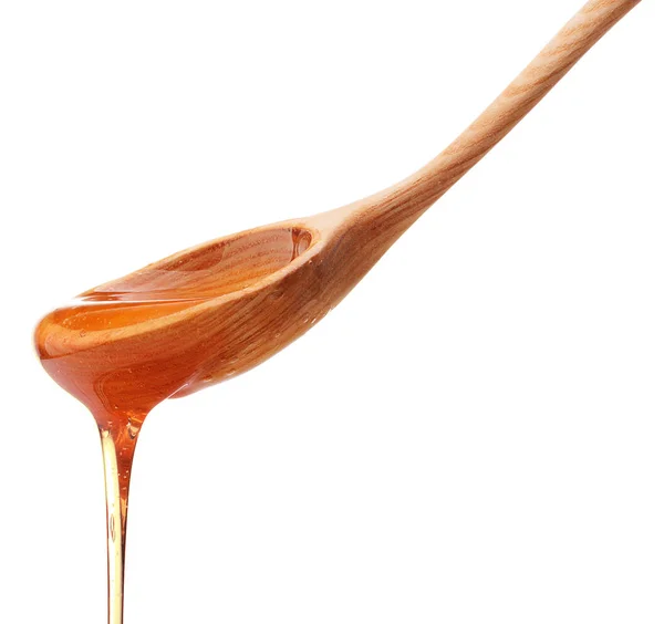 Мед капает с деревянной ложки — стоковое фото