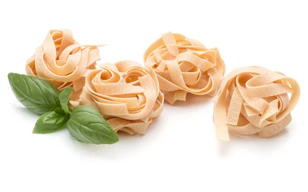 Italské těstoviny fettuccine hnízdo a bazalkovými listy — Stock fotografie