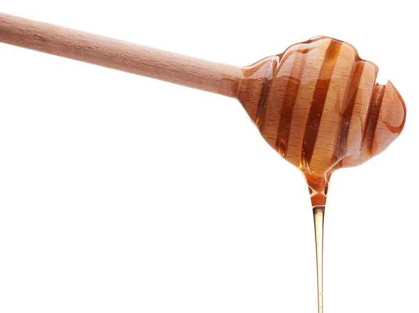Honey dripping from wooden dipper — Stock Photo, Image
