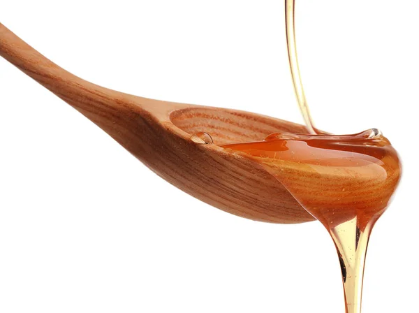 Honey dripping from wooden dipper — Stock Photo, Image