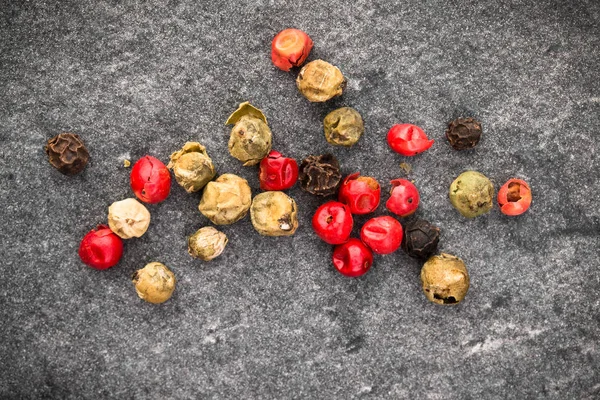 Peppercorns over black stone background. — Stock Photo, Image