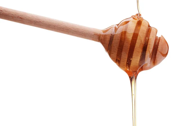 Honey dripping from wooden honey dipper — Stock Photo, Image