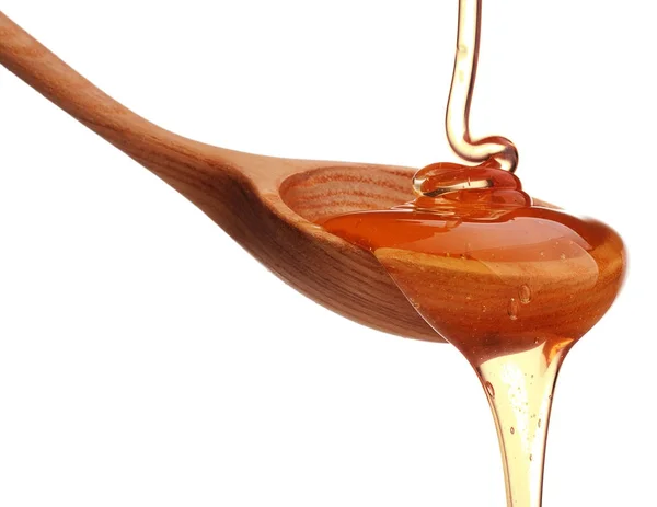 Honey dripping from wooden honey dipper — Stock Photo, Image