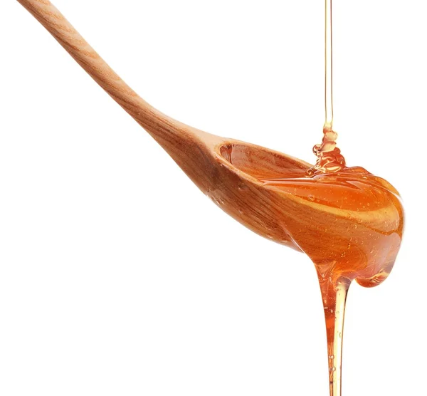 Honey dripping from wooden honey dipper — Stock Photo, Image