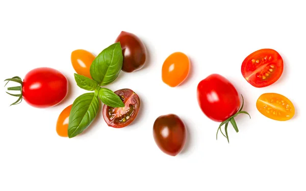 Vários tomates coloridos e folhas de manjericão isolado sobre b branco — Fotografia de Stock