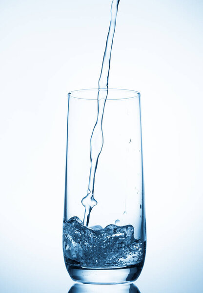 water pouring into glass over blue background.