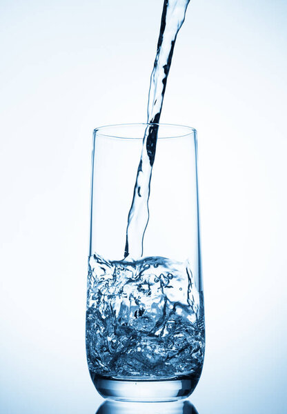 water pouring into glass on blue background