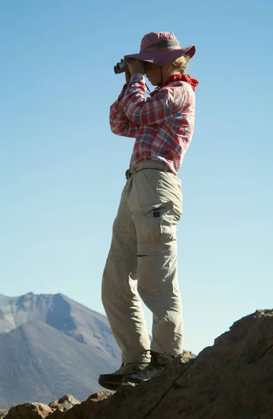 Unga kvinnliga resenären använder kikare i bergen — Stockfoto