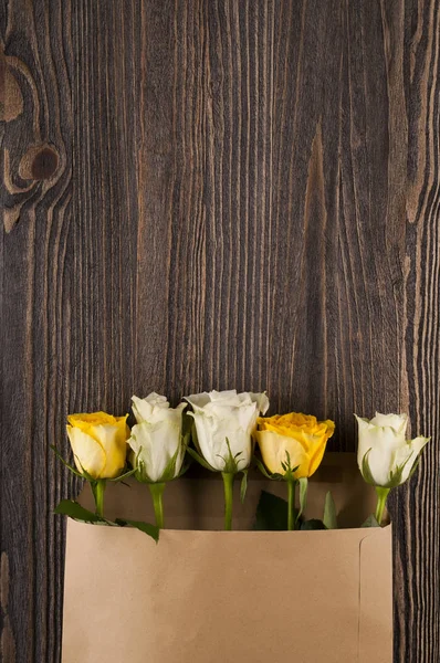 Букет з різнокольорових троянд в паперовій конверті над дерев'яною б — стокове фото