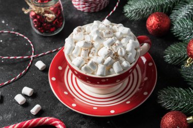 Kırmızı bardakta marşmelovlu kakao siyah bir masada Noel süslemeleri ile. Kırmızı kompozisyon. Noel kartı konsepti