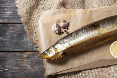 Kahverengi ahşap bir masadaki tahta bir tahtanın üzerinde tütsülenmiş balık yumurtası. Kapatın. Metin için boşluk olan üst görünüm