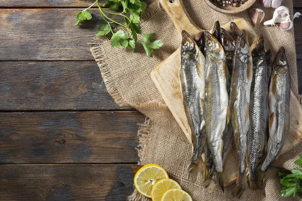 Kahverengi ahşap bir masanın üzerinde tütsülenmiş ya da kurutulmuş eritilmiş balık. Metin için boşluk olan üst görünüm