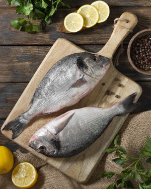 Raw Dorado fish on a wooden Board on a brown wooden table. Cooking process. Top view with space for text