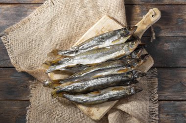Kahverengi ahşap bir masanın üzerinde tütsülenmiş ya da kurutulmuş eritilmiş balık. Metin için boşluk olan üst görünüm