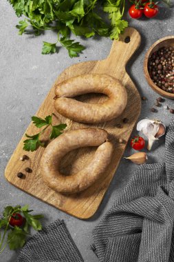 Baharatlı sosis ve maydanozlu tahta bir tahta üzerinde gri mutfak arka planında. Metin için boşluk olan üst görünüm