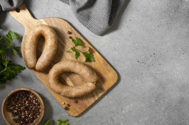 Baharatlı sosis ve maydanozlu tahta bir tahta üzerinde gri mutfak arka planında. Metin için boşluk olan üst görünüm