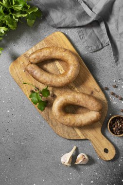 Baharatlı sosis ve maydanozlu tahta bir tahta üzerinde gri mutfak arka planında. Metin için boşluk olan üst görünüm