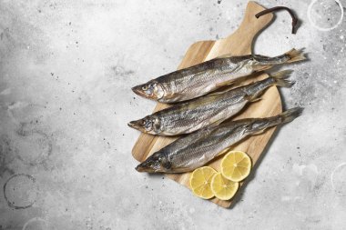 Gri bir mutfak masasında ahşap bir tahtanın üzerinde füme ya da kurutulmuş eritilmiş balık. Metin için boşluk olan üst görünüm