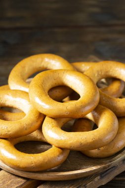 Kahverengi ahşap bir masada tahta bir tabakta simit. Kırsal tarzda. Ev yapımı kek.