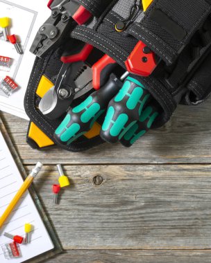 Alet gereçleri, gri ahşap bir masaya kurulmuş. Elektrik kurulumu için inşaat araçlarıyla dolu çanta