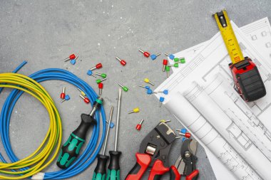 Elektrik kablolarını sıkıştırmak için farklı boylarda ve renklerde aletler ve uçlar. Gri beton arka planda kripto aletleri, kablo uçları ve elektrik kablosu