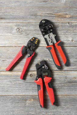 Elektrik kablolarını sıkıştırmak için kullanılan aletler. Gri ahşap arka planda elektrikçi veya inşaatçı için kripto araçları