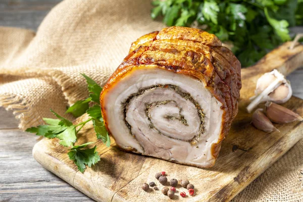 Gri ahşap bir masada, tahta bir tahtanın üzerinde sebzeli ve otlu rulo köfte. Pişmiş et. Metin için boşluk olan üst görünüm. Dikey oryantasyon. Kırsal biçim