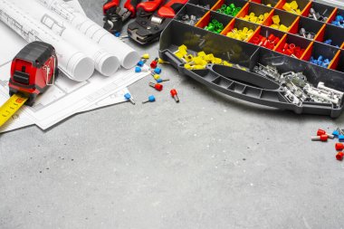 Çok çekirdekli elektrik kablolarını sıkıştırmak için çeşitli boyut ve renklerde ucu olan kripto aletleri ve kutular. Gri beton arka planda kripto aletleri, kablo uçları ve elektrik kablosu