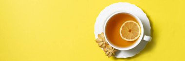 Sarı arka planda beyaz bardakta limonlu çay. Metin için boşluk olan üst görünüm. Site için pankart
