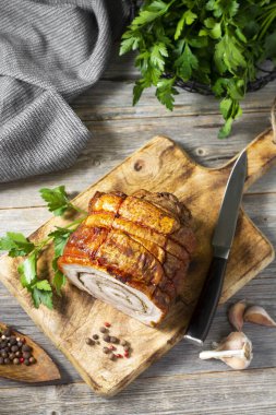 Gri ahşap bir masada, tahta bir tahtanın üzerinde sebzeli ve otlu rulo köfte. Pişmiş et. Metin için boşluk olan üst görünüm. Dikey oryantasyon. Kırsal biçim