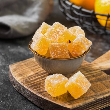 Tahta bir tahtanın üzerindeki kaseye şeker serpiştirilmiş marmelat. Koyu arkaplan