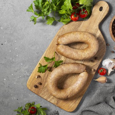 Baharatlı sosis ve maydanozlu tahta bir tahta üzerinde gri mutfak arka planında. Metin için boşluk olan üst görünüm