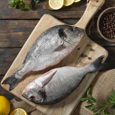 Raw Dorado fish on a wooden Board on a brown wooden table. Cooking process. Top view with space for text