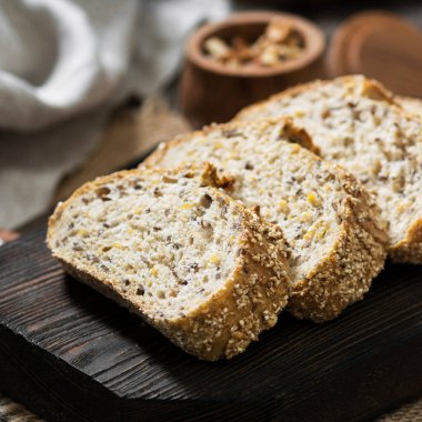 Ahşap mutfak masasında tahta bir tahtanın üzerinde dilimlenmiş ekmek. Kırsal biçim