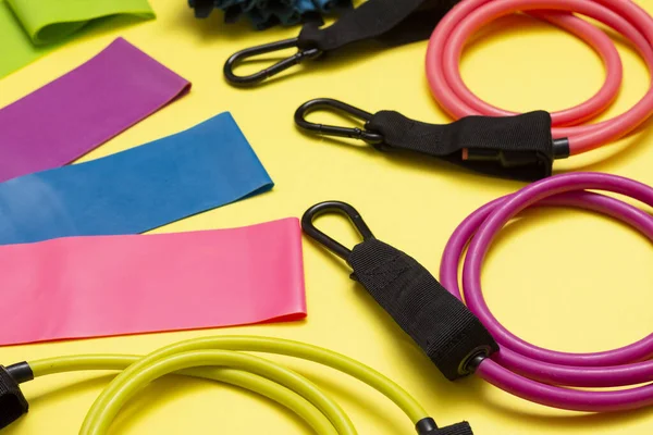 Expanders and elastic bands for fitness with different degrees of load on a yellow background. Elastic bands for fitness. Sports equipment for sports activities