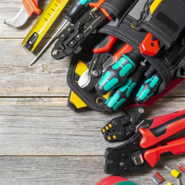 Alet gereçleri, gri ahşap bir masaya kurulmuş. Elektrik kurulumu için inşaat araçlarıyla dolu çanta