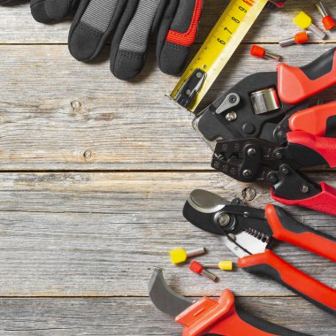 Gri ahşap bir masada elektrikçi ya da inşaatçının aletleri. Gri arka planda tamir için inşaat aletleri. Metin için boşluk olan üst görünüm