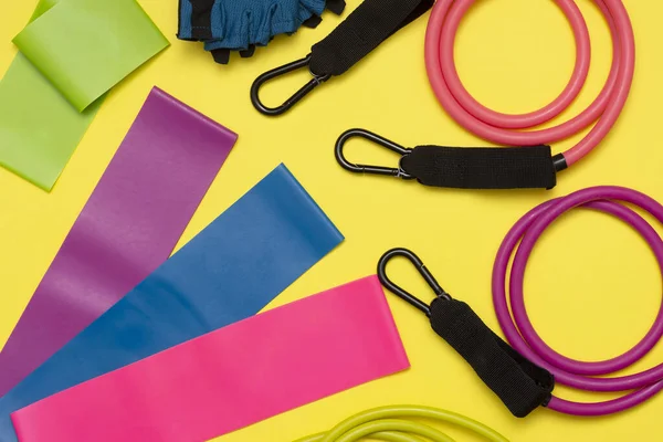 Expanders and elastic bands for fitness with different degrees of load on a yellow background. Elastic bands for fitness. Sports equipment for sports activities