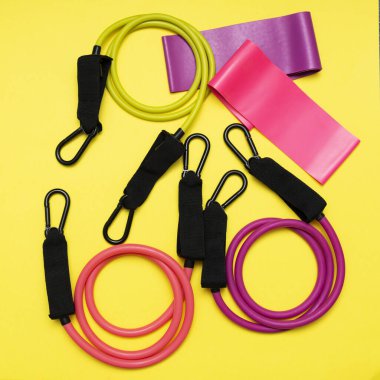 Genişleticiler ve elastik bantlar, sarı arka planda farklı derecelerde yükleme için. Spor için elastik bantlar. Spor faaliyetleri için spor ekipmanları