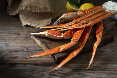 Kahverengi ahşap bir masada, koyu kahverengi bir tahtada yengeç eti. Karanlık arka plan. Yengeçle hayat