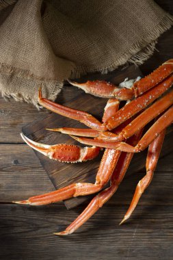 Kahverengi ahşap bir masada, koyu kahverengi bir tahtada yengeç eti. Karanlık arka plan. Yengeçle hayat. Metin için boşluk olan üst görünüm