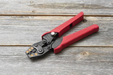 Gri ahşap masadaki bir elektrikçi için kripto aleti. Pense ya da penseye kol uçları için bastır. Elektrikçi ya da inşaatçı için bir araç. Metin için boşluk olan üst görünüm