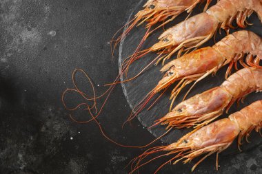 Siyah mutfak masasının üstünde siyah bir tabakta büyük Langoustines. Sağlıklı beslenme için deniz ürünleri