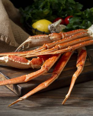 Kahverengi ahşap bir masada, koyu kahverengi bir tahtada yengeç eti. Karanlık arka plan. Yengeçle hayat