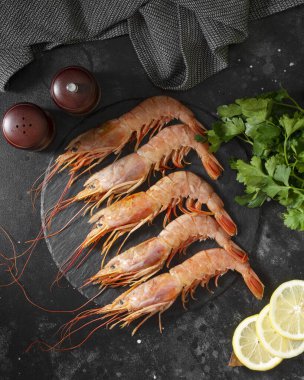 Siyah mutfak masasının üstünde siyah bir tabakta büyük Langoustines. Sağlıklı beslenme için deniz ürünleri