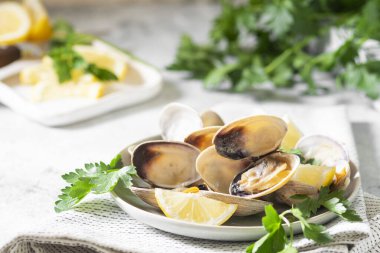 Açık gri bir masada seramik tabakta istiridye pişirdim. Deniz ürünleri yemeği.